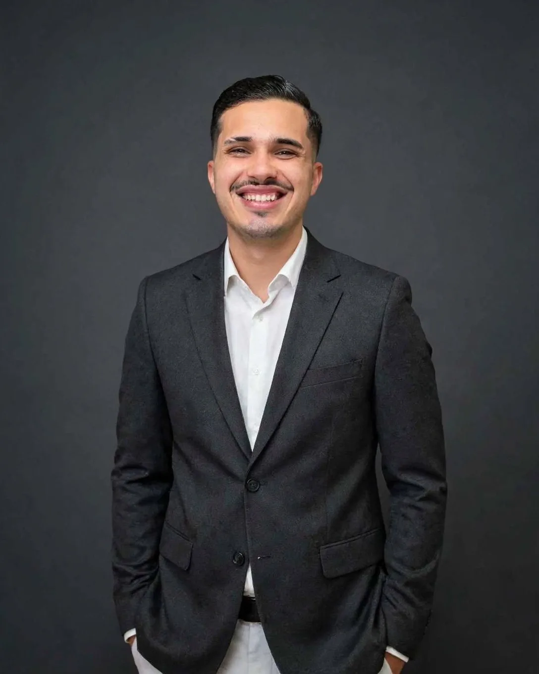 Alex Ferreira, consultor da AM Consórcios, sorrindo, de blazer escuro e camisa branca